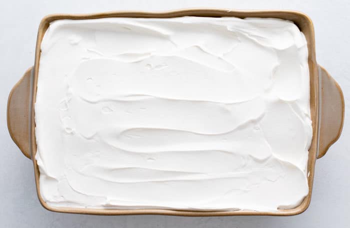 Overhead view of baking dish with whipped cream spread out inside of it.