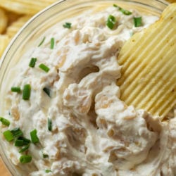 A bowl of French Onion Dip with a Chip in it and a label of the recipe name on top.