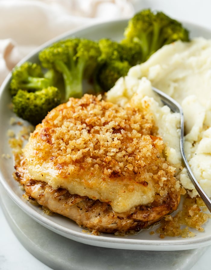 A white plate with Parmesan Crusted Chicken and Broccoli in the background.