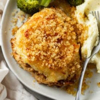 Longhorn Parmesan Crusted Chicken next to mashed potatoes and a fork on a plate.