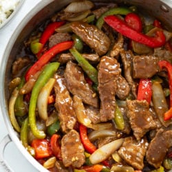 A skillet filled with Pepper Steak in a brown sauce with onions and peppers.